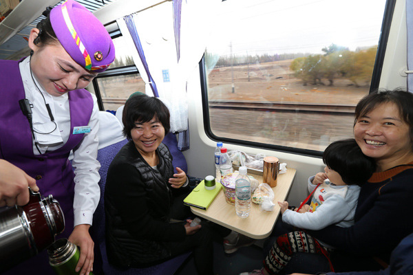 An attendant serves passengers on a train running between Urumqi and Kuerle in the Xinjiang Uygur autonomous region. (Photo by Li Xiongxin/For China Daily) An attendant serves passengers on a train running between Urumqi and Kuerle in the Xinjiang Uygur autonomous region. (Photo by Li Xiongxin/For China Daily)