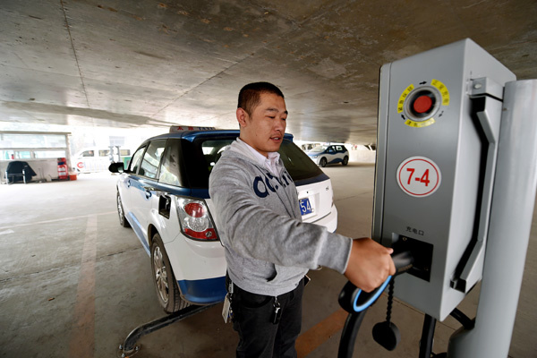 A taxi driver charges his electric vehicle at a charging post in Taiyuan, Shanxi province, on Oct 19. The city initiated a move last year to replace gasoline and hybrid taxis with purely electric ones. Currently, 97 percent of taxis in the city are purely electric. (Photo by Zhan Yan/Xinhua) A taxi driver charges his electric vehicle at a charging post in Taiyuan, Shanxi province, on Oct 19. The city initiated a move last year to replace gasoline and hybrid taxis with purely electric ones. Currently, 97 percent of taxis in the city are purely electric. (Photo by Zhan Yan/Xinhua)