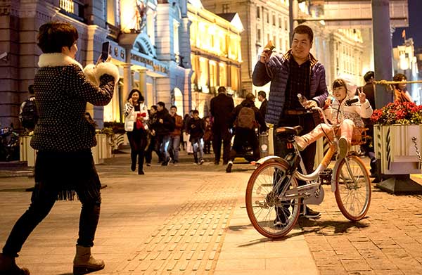 A girl poses for a photo while sitting in the basket of a bike owned by Mobike, a bike-sharing service provider, at the Bund in Shanghai on New Year's Eve.Gao Erqiang / China Daily A girl poses for a photo while sitting in the basket of a bike owned by Mobike, a bike-sharing service provider, at the Bund in Shanghai on New Year's Eve.Gao Erqiang / China Daily