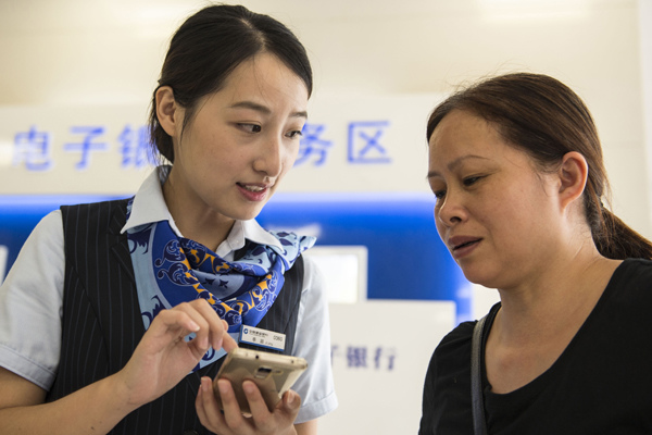 An employee of China Construction Bank helps a client at a branch in Haian, Jiangsu province. (Photo by Xu Jinbai/For China Daily) An employee of China Construction Bank helps a client at a branch in Haian, Jiangsu province. (Photo by Xu Jinbai/For China Daily)