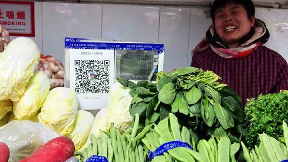 A vendor in a vegetable market shows the QR code for WeChat Pay. (Photo/CGTN) A vendor in a vegetable market shows the QR code for WeChat Pay. (Photo/CGTN)