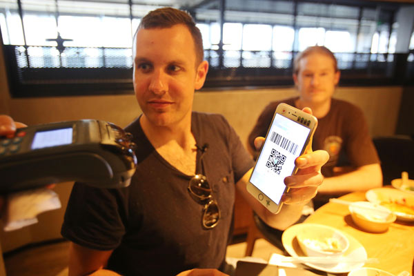 Tim Clancy, from Australia, pays a bill with his smartphone at a restaurant in Hangzhou, Zhejiang province, on Friday. (Photo provided to China Daily) Tim Clancy, from Australia, pays a bill with his smartphone at a restaurant in Hangzhou, Zhejiang province, on Friday. (Photo provided to China Daily)