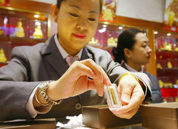 A worker displays a gold bar at a department store in Beijing. JIANG DONG / FOR CHINA DAILY A worker displays a gold bar at a department store in Beijing. JIANG DONG / FOR CHINA DAILY