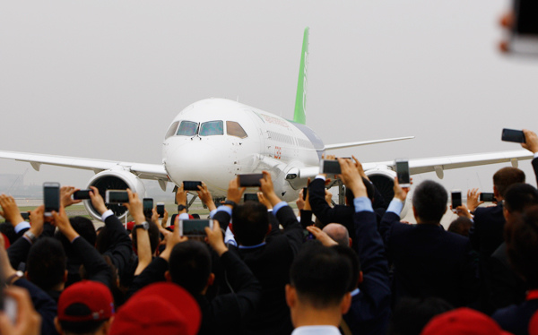 Guests vie to take photos of the C919 after its successful maiden test flight and landing at the Shanghai Pudong International Airport on Friday. FANG ZHE / XINHUA Guests vie to take photos of the C919 after its successful maiden test flight and landing at the Shanghai Pudong International Airport on Friday. FANG ZHE / XINHUA