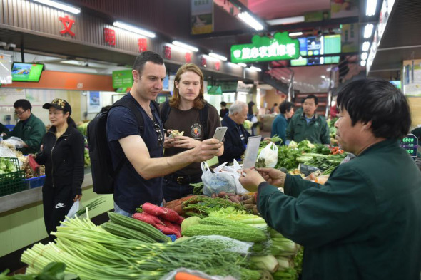 Foreigners experience using mobile payments to buy vegetables at a marketplace in Hangzhou, Zhejiang province, on April 14, 2017. (Photo/Xinhua) Foreigners experience using mobile payments to buy vegetables at a marketplace in Hangzhou, Zhejiang province, on April 14, 2017. (Photo/Xinhua)