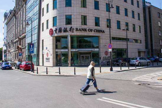Photo taken shows a passerby walking in front of the Poland branch of the Bank of China in Warsaw, the country’s capital city. Officially started operation on June 6, 2012, the bank has had full access to the financial market of Poland, providing high-quality financial services for Chinese and Polish clients from the industrial, commercial and financial sectors as well as for individual customers. Its services include deposit, loan, remittance of local and foreign currencies, foreign exchange transactions, trade finance, and guarantee, etc. The branch is the first Chinese bank officially operating in Poland. (Photo by Xinhua News Agency) Photo taken shows a passerby walking in front of the Poland branch of the Bank of China in Warsaw, the country’s capital city. Officially started operation on June 6, 2012, the bank has had full access to the financial market of Poland, providing high-quality financial services for Chinese and Polish clients from the industrial, commercial and financial sectors as well as for individual customers. Its services include deposit, loan, remittance of local and foreign currencies, foreign exchange transactions, trade finance, and guarantee, etc. The branch is the first Chinese bank officially operating in Poland. (Photo by Xinhua News Agency)