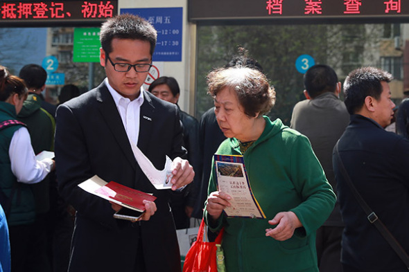 A housing agent helps a client complete property transactions in Beijing. (Photo/China Daily) A housing agent helps a client complete property transactions in Beijing. (Photo/China Daily)