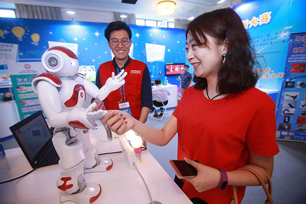 A visitor shakes hands with a robot during a science and technology week in Beijing. (Photo/China Daily) A visitor shakes hands with a robot during a science and technology week in Beijing. (Photo/China Daily)
