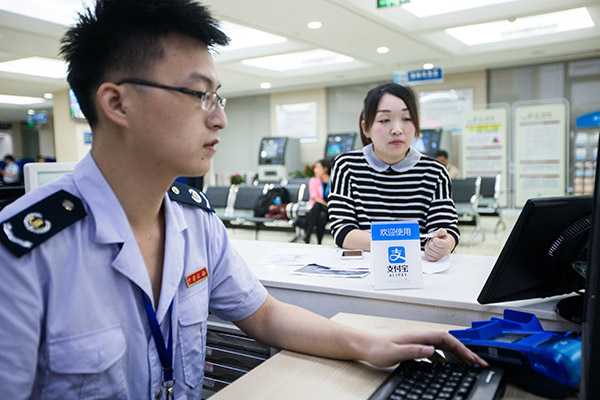A public servant deals with a tax bill paid through Alipay in Xihu branch of the taxation bureau in Hangzhou, Zhejiang province. (Photo/China Daily) A public servant deals with a tax bill paid through Alipay in Xihu branch of the taxation bureau in Hangzhou, Zhejiang province. (Photo/China Daily)