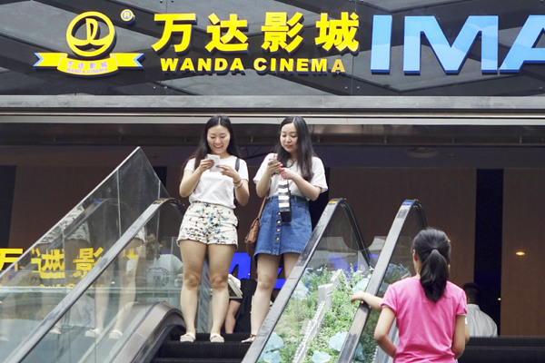 Two moviegoers check their mobile phones at a Wanda cinema in Zhengzhou, capital of Henan province. (Photo provided to CHINA DAILY) Two moviegoers check their mobile phones at a Wanda cinema in Zhengzhou, capital of Henan province. (Photo provided to CHINA DAILY)