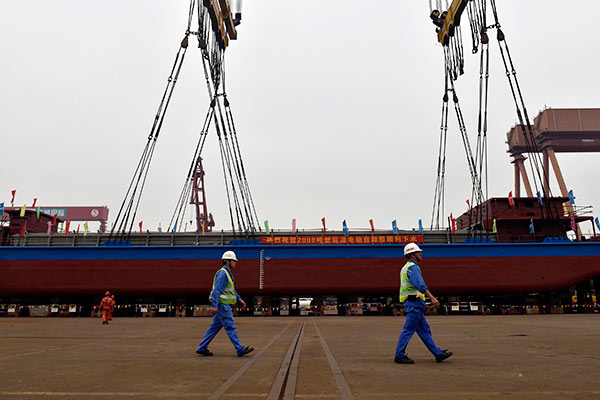 Two technicians pass by the world's first 2,000-metric-ton all-electric cargo ship during its debut in Guangzhou, capital city of Guangdong province. The ship can run 80 kilometers after being fully charged. (Photo/China Daily) Two technicians pass by the world's first 2,000-metric-ton all-electric cargo ship during its debut in Guangzhou, capital city of Guangdong province. The ship can run 80 kilometers after being fully charged. (Photo/China Daily)