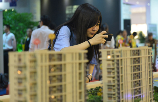 A Hangzhou denizen takes pictures of models of a housing estate at a sales center. (Photo provided to China Daily) A Hangzhou denizen takes pictures of models of a housing estate at a sales center. (Photo provided to China Daily)