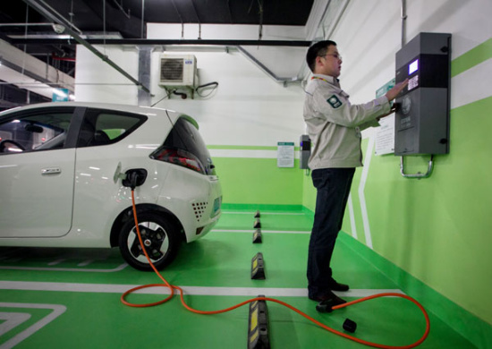 A technician from State Grid Shanghai Municipal Electric Power Co inspects the charging piles, or power ports, in a parking lot before they are put into operation. (Photo/Xinhua)