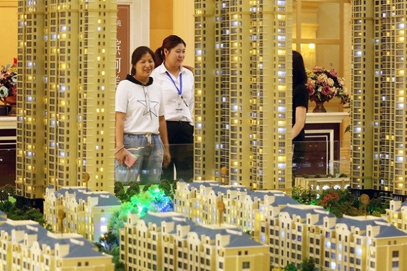 A saleswoman (center) talks with customers at a real estate sales office in Huai'an, Jiangsu province. (Photo by Zhou Changguo/China News Service)