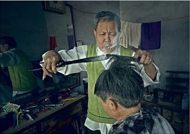 Wang Weimei, a barber, uses burning tongs to perm hair for his customers. (Photo/Chengdu Business Daily) Wang Weimei, a barber, uses burning tongs to perm hair for his customers. (Photo/Chengdu Business Daily)