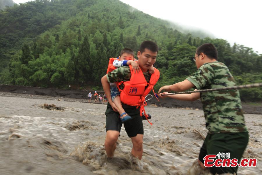 Rescuers help evacuate hikers stranded by rising floodwaters after rainstorms in a valley in Southwest China’s Chongqing municipality, June 1, 2015. A total of 18 tourists, including six children, were trapped by floods and later saved by rescuers. (Photo: China News Service/Huang Xing)