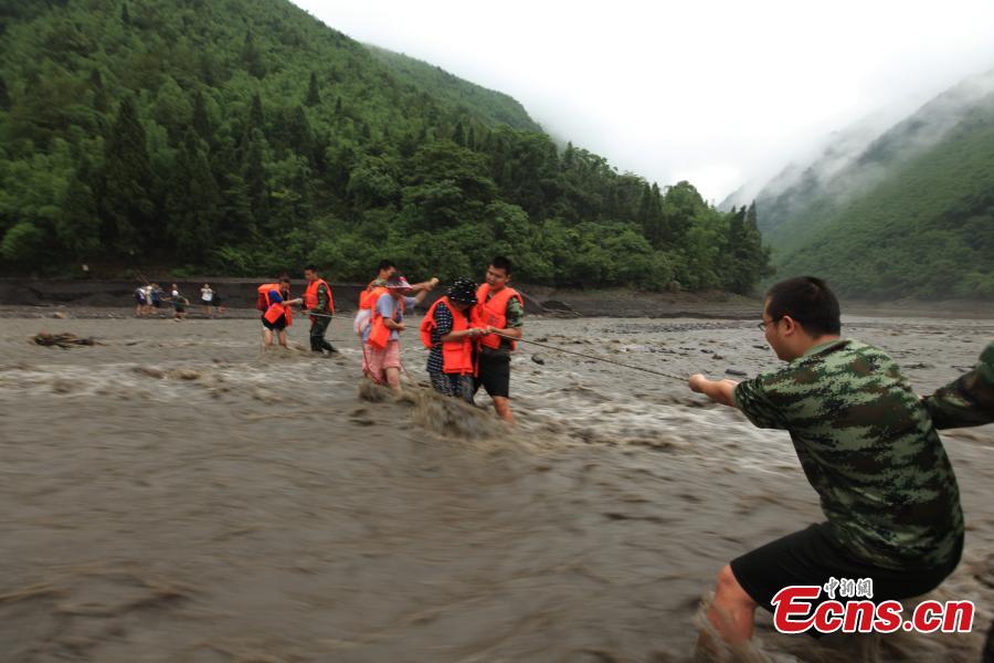 Rescuers help evacuate hikers stranded by rising floodwaters after rainstorms in a valley in Southwest China’s Chongqing municipality, June 1, 2015. A total of 18 tourists, including six children, were trapped by floods and later saved by rescuers. (Photo: China News Service/Huang Xing)