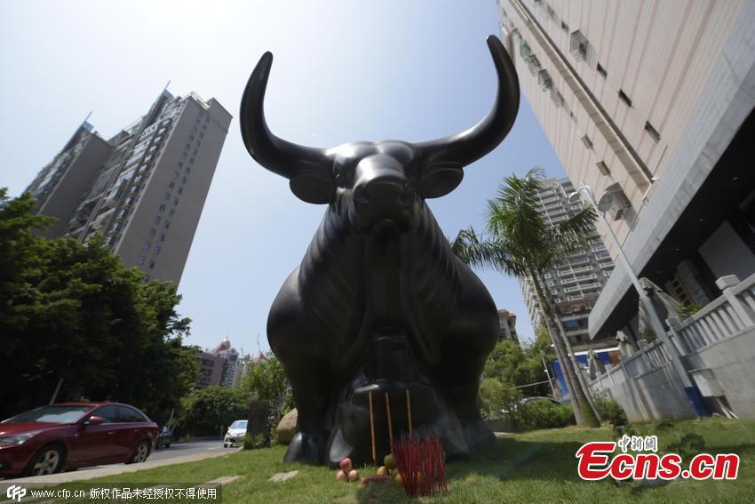 Stock investors pray to bull-over-bear sculpture for market rebound (1/3)
