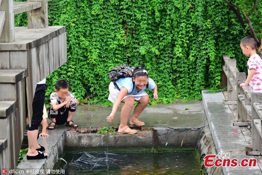 Unruly tourists catch goldfish in park(1/4)
