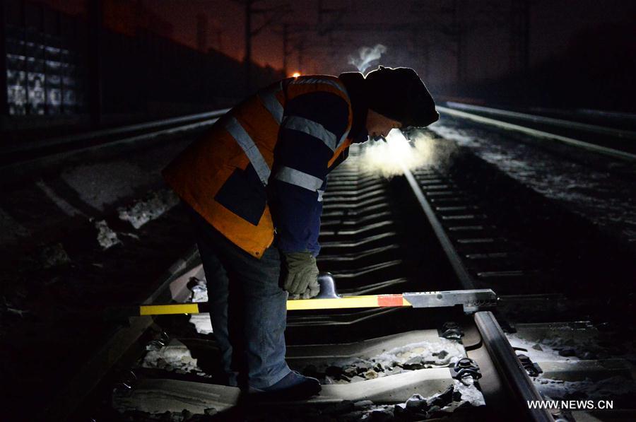 Workers examine railway track before dawn due to cold weather in NE China (1/10)