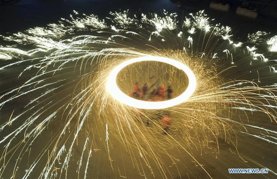Performers spray burning iron chips to shower sparks-like fireworks (1/4)