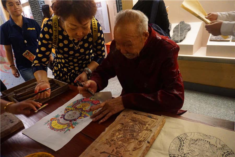 Chen Yiwen signs his name on one of his works. (Photo/chinadaily.com.cn)