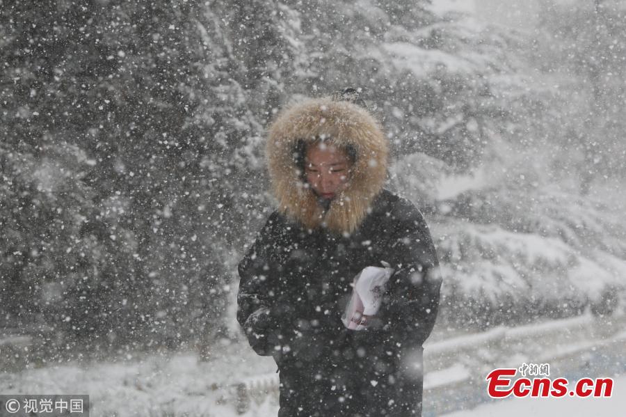 Pedestrians walk amid snowfall in Yantai, east China\'s Shandong Province, Dec. 11, 2017. A cold wave brought a heavy snowfall here.(Photo/VCG)
