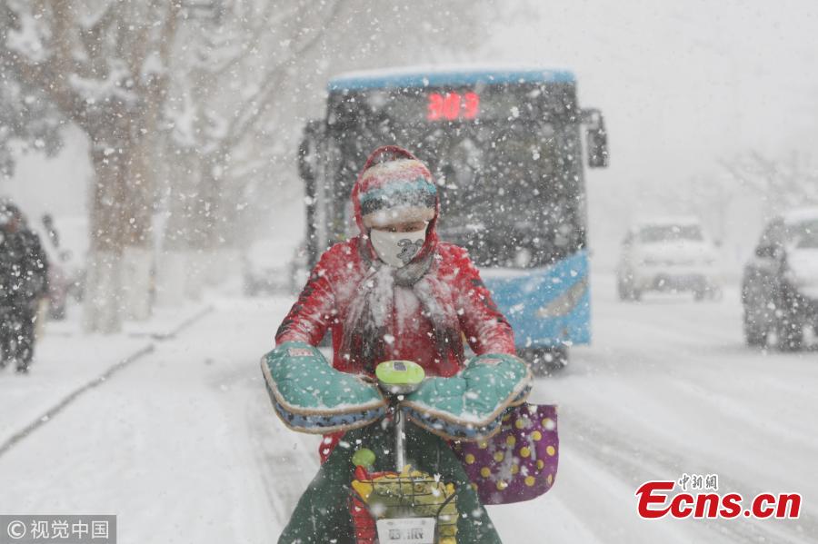 
Pedestrians walk amid snowfall in Yantai, east China\'s Shandong Province, Dec. 11, 2017. A cold wave brought a heavy snowfall here.(Photo/VCG)