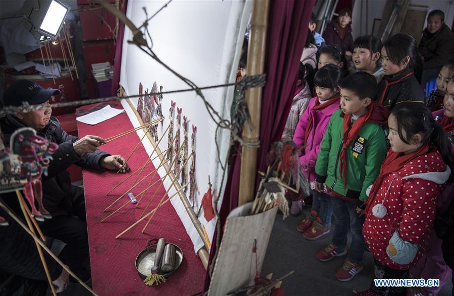 Children watch shadow puppet play accompanied by Pingli folk opera(1/7)