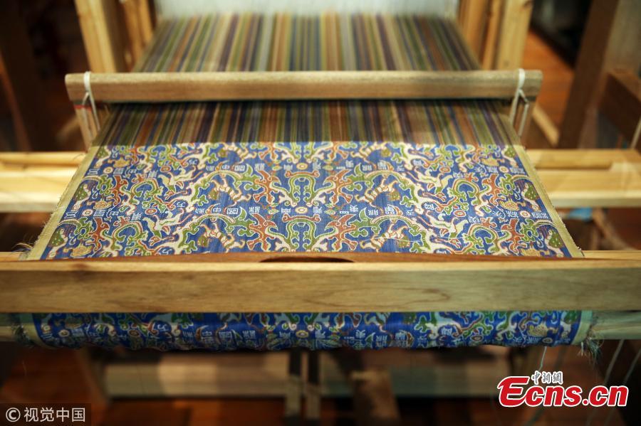 A replica of a colorful brocade embroidered with the text “Wuxing Chu Dongfang Li Zhongguo”, which literary means \