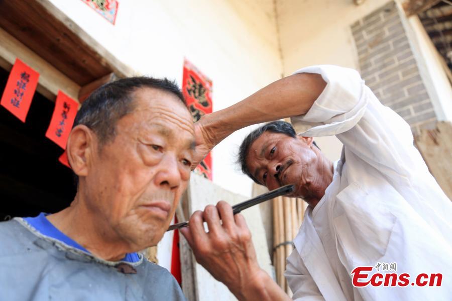 Barber Hu Daofa cuts a man’s hair at a village in Zhuangbu Countryside, Huichang County, East China’s Jiangxi Province. Hu, 73, started travelling around nearby villages offering door-to-door haircutting, shaving, and ear-cleaning in 1966, charging an annual fee of 130 yuan for three visits a month. Hu can’t ride a bicycle, so he walks. Most of his customers are children and elderly people. (Photo: China News Service/Jiang Tao)