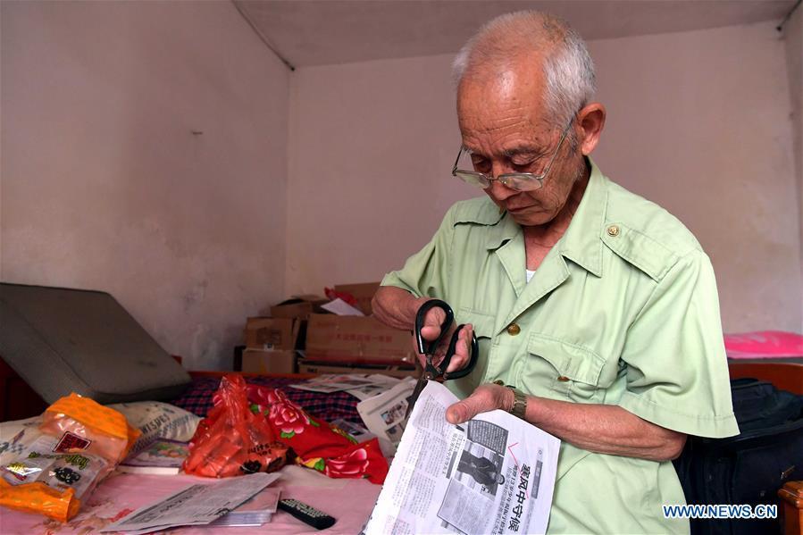 Miao Yanxiang cuts down a report of good deeds to read for children at the caring station for left-behind children at his home in Shibu Town, Nanchang City of east China\'s Jiangxi Province, May 23, 2018. Miao, over 70, established a caring station for left-behind children at his own house in 2009, where he provided free place for children to do homework and study after school. Having received more than 3,000 children over the past nine years, Miao is satisfied with his voluntary work as he see the progress of the children. (Xinhua/Peng Zhaozhi)
