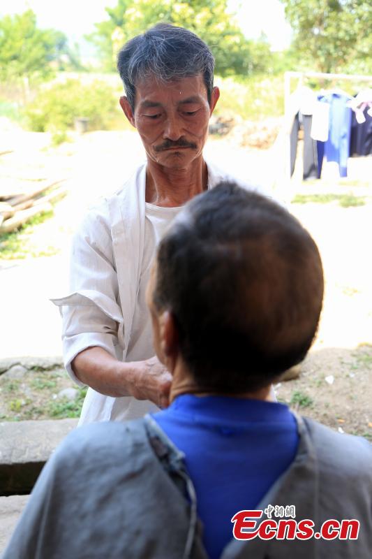 Barber Hu Daofa cuts a man’s hair at a village in Zhuangbu Countryside, Huichang County, East China’s Jiangxi Province. Hu, 73, started travelling around nearby villages offering door-to-door haircutting, shaving, and ear-cleaning in 1966, charging an annual fee of 130 yuan for three visits a month. Hu can’t ride a bicycle, so he walks. Most of his customers are children and elderly people. (Photo: China News Service/Jiang Tao)
