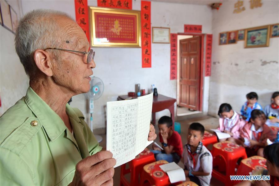 Miao Yanxiang displays well-done homework at the caring station for left-behind children at his home in Shibu Town, Nanchang City of east China\'s Jiangxi Province, May 23, 2018. Miao, over 70, established a caring station for left-behind children at his own house in 2009, where he provided free place for children to do homework and study after school. Having received more than 3,000 children over the past nine years, Miao is satisfied with his voluntary work as he see the progress of the children. (Xinhua/Peng Zhaozhi)