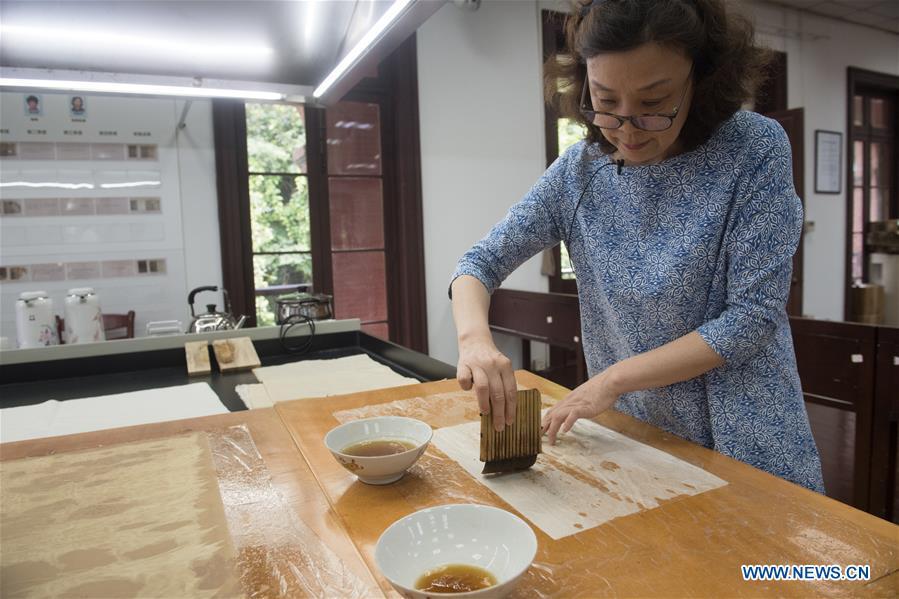 Yan Jingshu dyes restoration paper at Zhejiang Library in Hangzhou, east China\'s Zhejiang Province, May 23, 2018. Yan, 55, has worked in the national level ancient book restoration center of the library for 38 years. She and her colleagues collected more than 200 types of paper to restore ancient books. (Xinhua/Weng Xinyang)