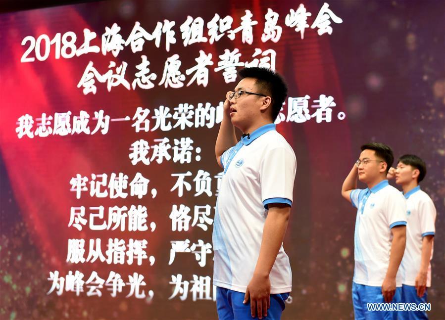 Volunteers take an oath during a launch ceremony for the volunteer program for the upcoming Shanghai Cooperation Organization (SCO) summit in Qingdao, east China\'s Shandong Province, May 24, 2018. About 2,000 volunteers will offer services such as assisting with guests\' arrival and departure, translation, and media requests during the 18th summit of the SCO. (Xinhua/Li Ziheng)