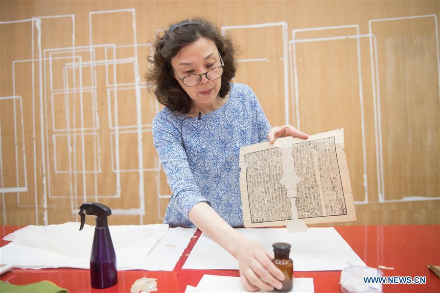 Yan Jingshu shows an ancient book under restoration at Zhejiang Library in Hangzhou, east China\'s Zhejiang Province, May 23, 2018. Yan, 55, has worked in the national level ancient book restoration center of the library for 38 years. She and her colleagues collected more than 200 types of paper to restore ancient books. (Xinhua/Weng Xinyang)