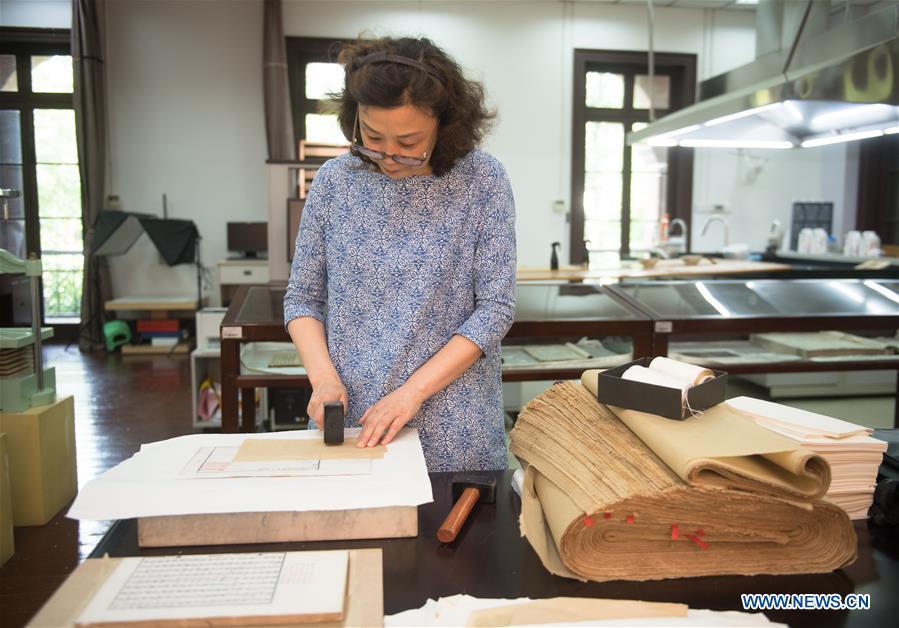 Yan Jingshu planishes an ancient book after restoration at Zhejiang Library in Hangzhou, east China\'s Zhejiang Province, May 23, 2018. Yan, 55, has worked in the national level ancient book restoration center of the library for 38 years. She and her colleagues collected more than 200 types of paper to restore ancient books. (Xinhua/Weng Xinyang)