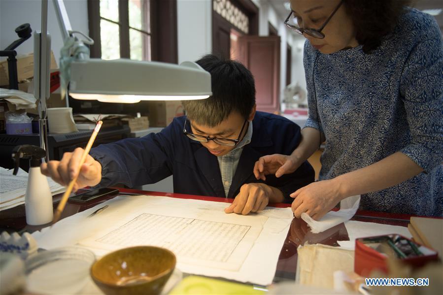 Yan Jingshu (R) instructs an apprentice in ancient book restoration at Zhejiang Library in Hangzhou, east China\'s Zhejiang Province, May 23, 2018. Yan, 55, has worked in the national level ancient book restoration center of the library for 38 years. She and her colleagues collected more than 200 types of paper to restore ancient books. (Xinhua/Weng Xinyang)