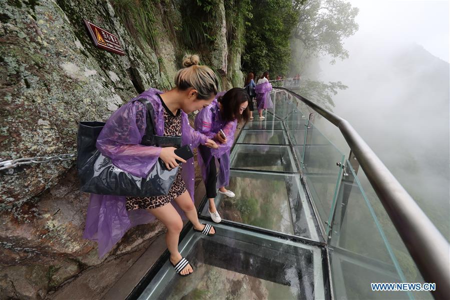 People look down the cliff through the Lingyundu glass trestle in the Xuedou Mountain in Ningbo City, east China\'s Zhejiang Province, May 26, 2018. The glass trestle was opened to tourists on Saturday. (Xinhua/Zhang Peijian)