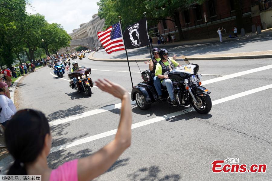 A woman waves at riders as thousands of military veterans and their supporters participate in the 31st annual Rolling Thunder motorcycle rally and Memorial Day weekend \