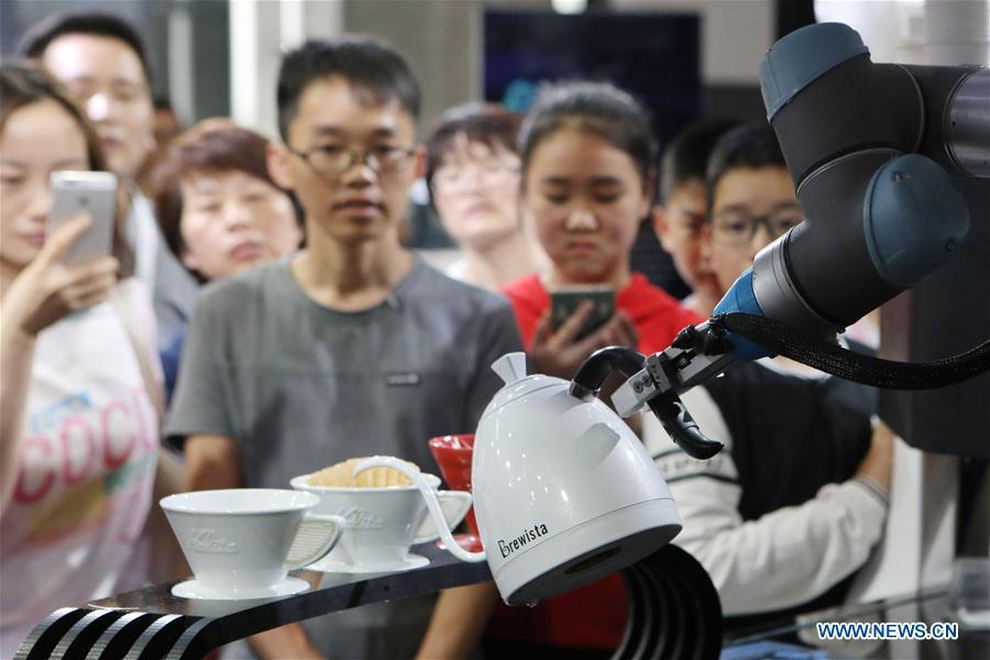 Visitors look at a coffee brewing robot during the 2018 China international big data industry expo in Guiyang, Southwest China\'s Guizhou province, May 26, 2018. The expo opened in Guiyang Saturday, attracting over 40,000 participants from nearly 30 countries. (Photo/Xinhua)