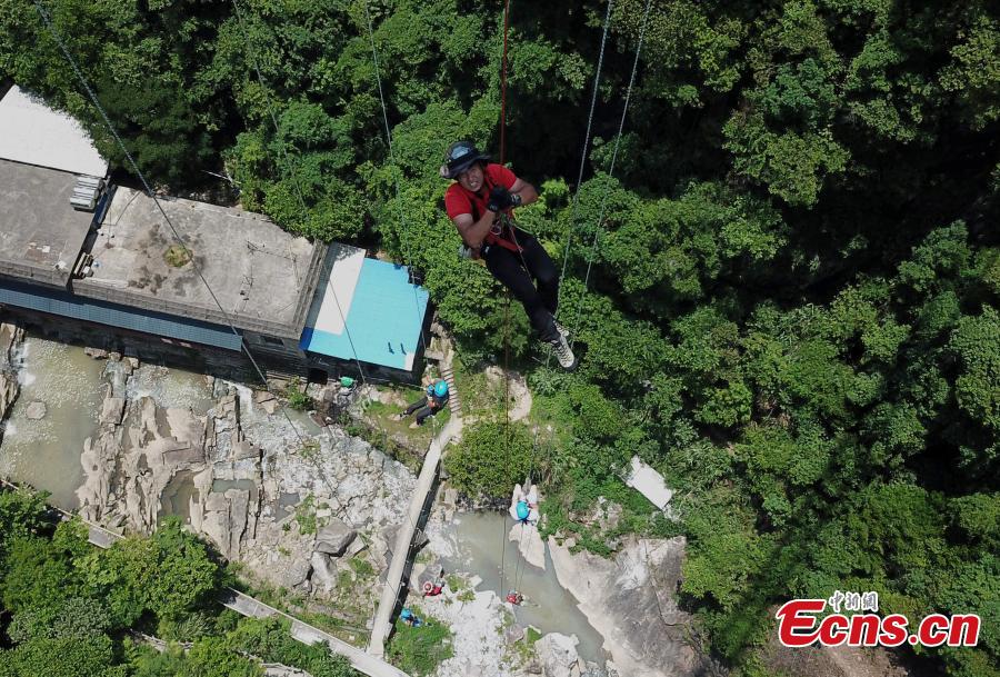Extreme sports enthusiasts take on the challenge of descending from and then climbing back to a suspended glass bridge 188 meters above the ground at a scenic spot in Youxi County, East China’s Fujian Province, May 26, 2018. More than 20 participants fast-roped down and then climbed back up from under the bottom of the bridge. (Photo: China News Service/Wang Dongming)