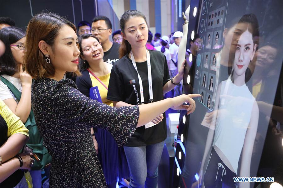 A visitor experiences a virtual fitting equipment of Alibaba during the 2018 China international big data industry expo in Guiyang, Southwest China\'s Guizhou province, May 26, 2018.(Photo/Xinhua)