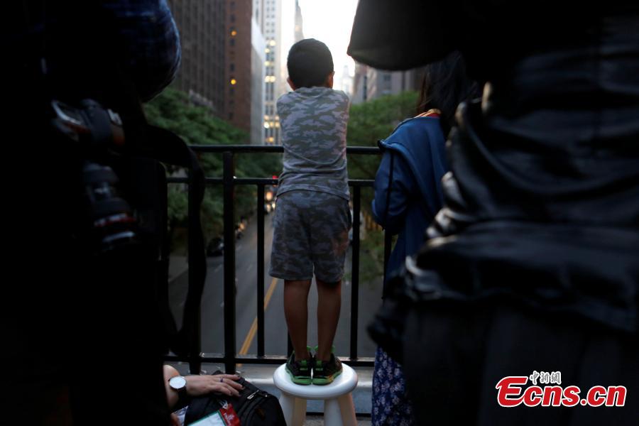 A boy stands on a footstool at Tudor City on 42nd St in Manhattan to watch the phenomenon known as Manhattanhenge in New York City, New York, U.S. May 29, 2018.(Photo/Agencies)