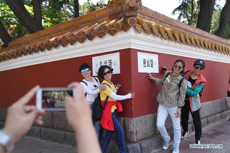 Tourists take photos at the corner of Daxue road and Yushan road in Qingdao, east China\'s Shandong Province, May 31, 2018. The 18th Shanghai Cooperation Organization (SCO) Summit is scheduled for June 9-10 in Qingdao. (Xinhua/Purbu Zhaxi)