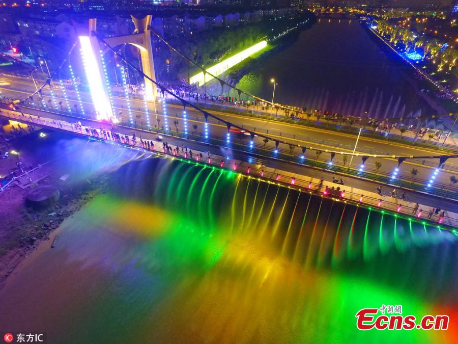 The Xiaolongwan suspension bridge is illuminated by a colorful lighting system in Jiangning District, Nanjing, Jiangsu Province, June 4, 2018. The 1,064-meter-long bridge has become a local attraction thanks to the amazing light show as well as a water spraying system operating from the bridge. (Photo/IC)