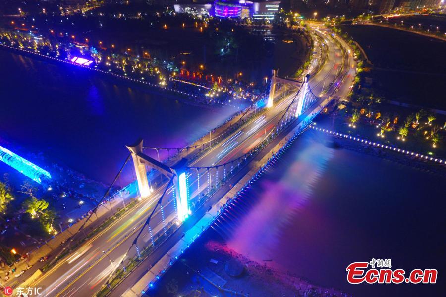 The Xiaolongwan suspension bridge is illuminated by a colorful lighting system in Jiangning District, Nanjing, Jiangsu Province, June 4, 2018. The 1,064-meter-long bridge has become a local attraction thanks to the amazing light show as well as a water spraying system operating from the bridge. (Photo/IC)