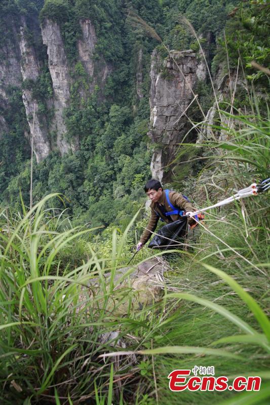 Sanitary worker Liu Wenhua collects garbage on a cliff while hanging from a cable at Wulingyuan scenic area in Zhangjiajie City, Central China’s Hunan Province, June 5, 2018. Liu, 48, has worked at the tourist attraction for nearly five years, mainly responsible for cleaning litter left by irresponsible visitors. (Photo: China News Service/Wu Yongbing)