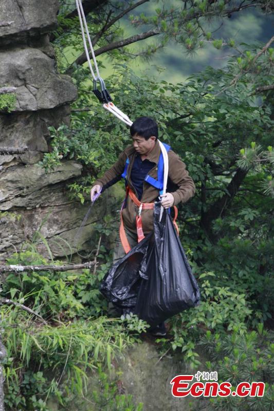 Sanitary worker Liu Wenhua collects garbage on a cliff while hanging from a cable at Wulingyuan scenic area in Zhangjiajie City, Central China’s Hunan Province, June 5, 2018. Liu, 48, has worked at the tourist attraction for nearly five years, mainly responsible for cleaning litter left by irresponsible visitors. (Photo: China News Service/Wu Yongbing)